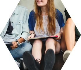 Jugendliche sitzen gemeinsam und lachen mit Tablet im Sekundarbereich der Schule am Auetal